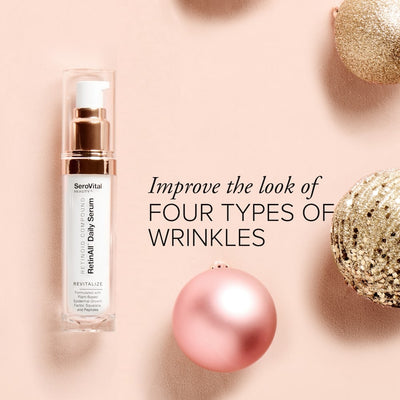 A bottle of retinoid serum RetinAll Daily Serum on a pink background with holiday ornaments and text that says Improve the look of four types of wrinkles